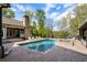 Inviting pool area with a jacuzzi, lush trees, a covered outdoor area, and a well-maintained brick patio at 7305 Breeze Bay Rd, Cumming, GA 30041