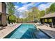 Luxury backyard featuring a long swimming pool, hot tub, and stylish outdoor seating with a beautiful garden backdrop at 7305 Breeze Bay Rd, Cumming, GA 30041