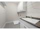 Clean laundry room featuring gray tile floors, white cabinets, and modern sink at 118 Brighton Blvd, Woodstock, GA 30188