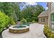 Backyard features a gorgeous pool, stone patio, a raised hot tub, and manicured greenery at 134 Lakestone Pkwy, Woodstock, GA 30188