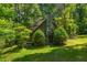 Cozy log cabin featuring a stone chimney and porch nestled among vibrant green foliage at 4728 Corn Creek Drive, Fairburn, GA 30213