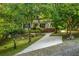 Charming single Gathering home with landscaped front yard, classic porch, and mature trees surrounding the property at 4728 Corn Creek Drive, Fairburn, GA 30213