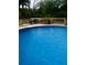 Inviting in-ground pool is fenced and has a small table and chairs for relaxing poolside at 15 Cobblestone Ct, Douglasville, GA 30134