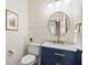 Charming half bathroom featuring a navy vanity, marble countertop, gold hardware and a decorative round mirror at 2759 Arbor Se Ave, Atlanta, GA 30317
