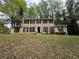 Traditional two-story home with tan siding, black shutters, and mature trees in a large front yard at 5183 Mccarter Ct, Stone Mountain, GA 30088