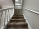 Carpeted staircase featuring a white handrail, leading to the upper level of the home at 5183 Mccarter Ct, Stone Mountain, GA 30088