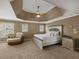 Spacious main bedroom with trey ceiling, large bed, nightstands, and sitting chair at 3544 Candytuft Run, Auburn, GA 30011