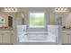 Luxurious bathroom with a soaking tub, granite counters, and stylish fixtures at 700 Relic Rdg, Hampton, GA 30228