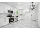 A modern kitchen with stainless steel appliances, white cabinets, and marble floors at 5935 Christopher Ln, Lithonia, GA 30058