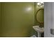 A quaint powder room with a pedestal sink and an oval mirror, complemented by soft lighting and green walls at 2195 Brickton Sta, Buford, GA 30518