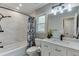 Bright bathroom featuring tiled walls, white cabinets, vanity, and a shower-tub combo with dark fixtures at 1484 W Prospect Dr, Lawrenceville, GA 30043
