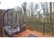 Exterior view of a wood deck with black metal railings and hanging papasan chair with a wooded view at 5883 Brookside Oak Cir, Norcross, GA 30093