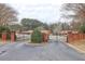 View of community entrance gate with brick columns, mature landscaping, and views of the building in the background at 5883 Brookside Oak Cir, Norcross, GA 30093
