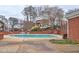 Community pool area featuring a sun deck with townhomes and mature trees in the background at 5883 Brookside Oak Cir, Norcross, GA 30093