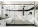 Walk-in shower with glass door, white tiled walls, black marble accents, and modern shower system, with soaking tub at 662 S Grand Nw Ave, Atlanta, GA 30318