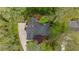 An aerial view of a home with a dark roof and a long driveway surrounded by mature trees and landscaped gardens at 11165 Bentley Chase Dr, Johns Creek, GA 30097