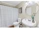 Bathroom with white vanity, pedestal sink, round mirror, and shower with white curtain at 11165 Bentley Chase Dr, Johns Creek, GA 30097