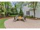 Stone fire pit with seating on a brick paver patio surrounded by mature trees at 11165 Bentley Chase Dr, Johns Creek, GA 30097