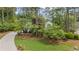A beautiful home with manicured lawn, mature trees, and a winding driveway presents an inviting curb appeal at 11165 Bentley Chase Dr, Johns Creek, GA 30097