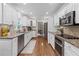 Galley kitchen featuring stainless appliances, granite counters, white cabinetry and tile backsplash at 11165 Bentley Chase Dr, Johns Creek, GA 30097