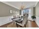 Inviting dining room with wainscotting, a modern chandelier, and a large window with natural light at 213 Roseman Way, Woodstock, GA 30188