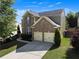 Two-story brick home with a two-car garage, showcasing mature trees and landscaping in a serene setting at 213 Roseman Way, Woodstock, GA 30188