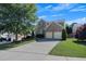 Two-story home with a two-car garage, showcasing a lush green lawn and mature trees on a sunny day at 213 Roseman Way, Woodstock, GA 30188