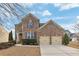 Traditional brick home featuring a two-car garage and manicured landscaping creating curb appeal at 213 Roseman Way, Woodstock, GA 30188