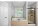 Bright bathroom featuring a soaking tub, a glass-enclosed shower, and neutral-toned tiled floors at 4350 Oakdale Vinings Se Cir, Smyrna, GA 30080