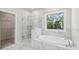 Spa-like bathroom with a soaking tub and glass-enclosed shower showcasing marble tiling at 4775 Columbia St, Cumming, GA 30040