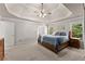 Large main bedroom with tray ceiling, carpeted floors, and natural light from surrounding windows at 975 Garden Crossing Ln, Cumming, GA 30040