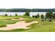 Scenic golf course view overlooking green and a serene lake with a golf cart parked nearby at 1517 Granby Ln, Locust Grove, GA 30248