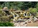 Scenic rock waterfall surrounded by lush greenery, creating a serene outdoor oasis at 1517 Granby Ln, Locust Grove, GA 30248