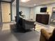 Finished basement with gray sofa, TV, door to utility room and painted concrete floor at 9 Buckhorn Dr, Temple, GA 30179