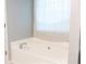 Relaxing bathtub with a neutral colored window curtain and natural light at 1043 Foxhollow Trl, Canton, GA 30115