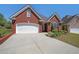 Charming brick home with a two-car garage, manicured landscaping, and a well-maintained lawn at 1610 Glenhurst Dr, Snellville, GA 30078
