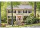 Charming two-story home with a red door and black shutters, surrounded by mature trees and lush landscaping at 2441 Mitchell Ne Rd, Marietta, GA 30062