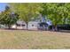 View of an older, single story ranch home with light paint on a large, grassy lot and mature trees at 1312 Harbins Rd, Dacula, GA 30019
