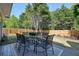 Outdoor patio with glass table and six chairs overlooking a grassy backyard and wooded area at 2525 Ashton Dr, Roswell, GA 30076