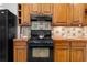 Traditional kitchen features wooden cabinets, black appliances, tile backsplash, and brick colored countertops at 446 Harold Ne Ave, Atlanta, GA 30307