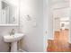 Stylish half bathroom with a pedestal sink and a view into a hallway with hardwood floors at 4609 Mctyre Way, Marietta, GA 30064