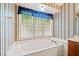 Bright bathroom featuring a soaking tub under a window with striped wall paper at 595 Saint James Se Walk, Marietta, GA 30067