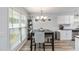 Cozy dining area features a modern chandelier, large window, and wood-look flooring next to the kitchen at 900 Hillary Ln, Lawrenceville, GA 30043