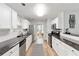 Bright kitchen featuring white cabinetry, granite countertops, stainless steel appliances, and wood-look floors at 900 Hillary Ln, Lawrenceville, GA 30043