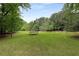 Large backyard with a trampoline, swing set and mature trees, perfect for outdoor activities at 9295 Martin Rd, Roswell, GA 30076