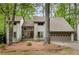 Inviting two-story home with stone accents, a two-car garage, and mature trees surrounding the property at 9295 Martin Rd, Roswell, GA 30076