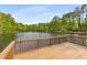 A wooden deck overlooks a serene lake surrounded by lush greenery and mature trees at 9295 Martin Rd, Roswell, GA 30076