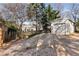 Backyard and gravel driveway featuring a detached garage, wood fence, and mature trees providing shade and privacy at 1763 Delaware Ne Ave, Atlanta, GA 30307