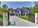Elegant two-story home with a black gated entrance, long driveway, and professionally landscaped front yard at 409 Thunder Rd, Buford, GA 30518