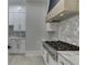 Close-up of a gas cooktop and marble countertops with white cabinets and gold hardware at 409 Thunder Rd, Buford, GA 30518
